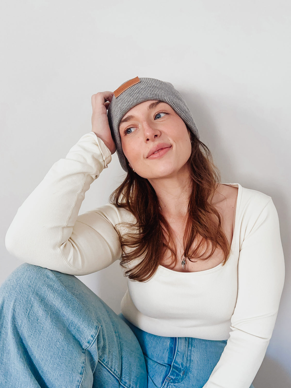 Woman wearing a gray beanie and white sweater against a plain background